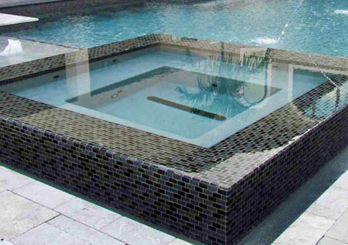 Raised glass-tile spa with travertine surround