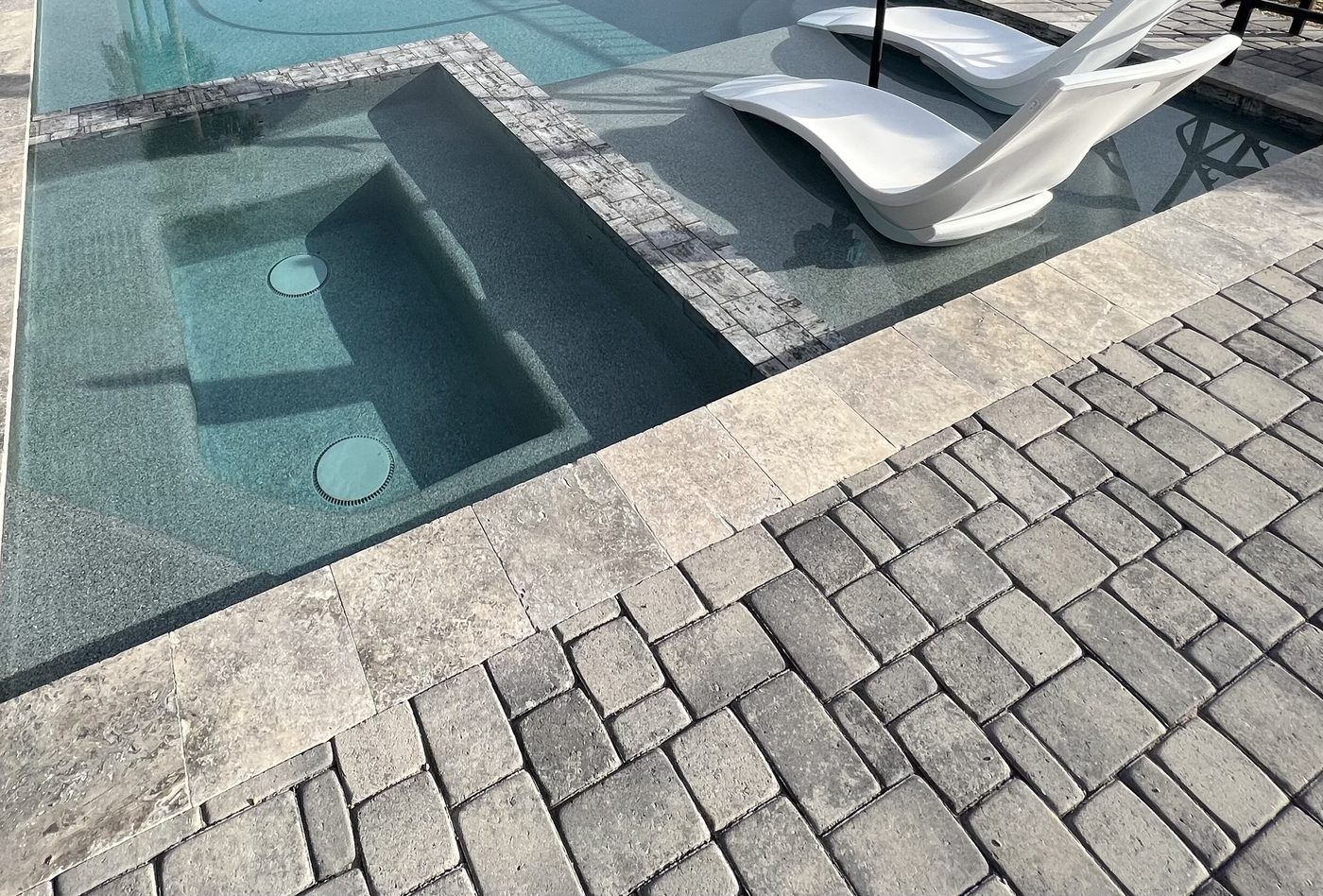 Concrete paver decking with loungers beside a spa — Standard Pools project