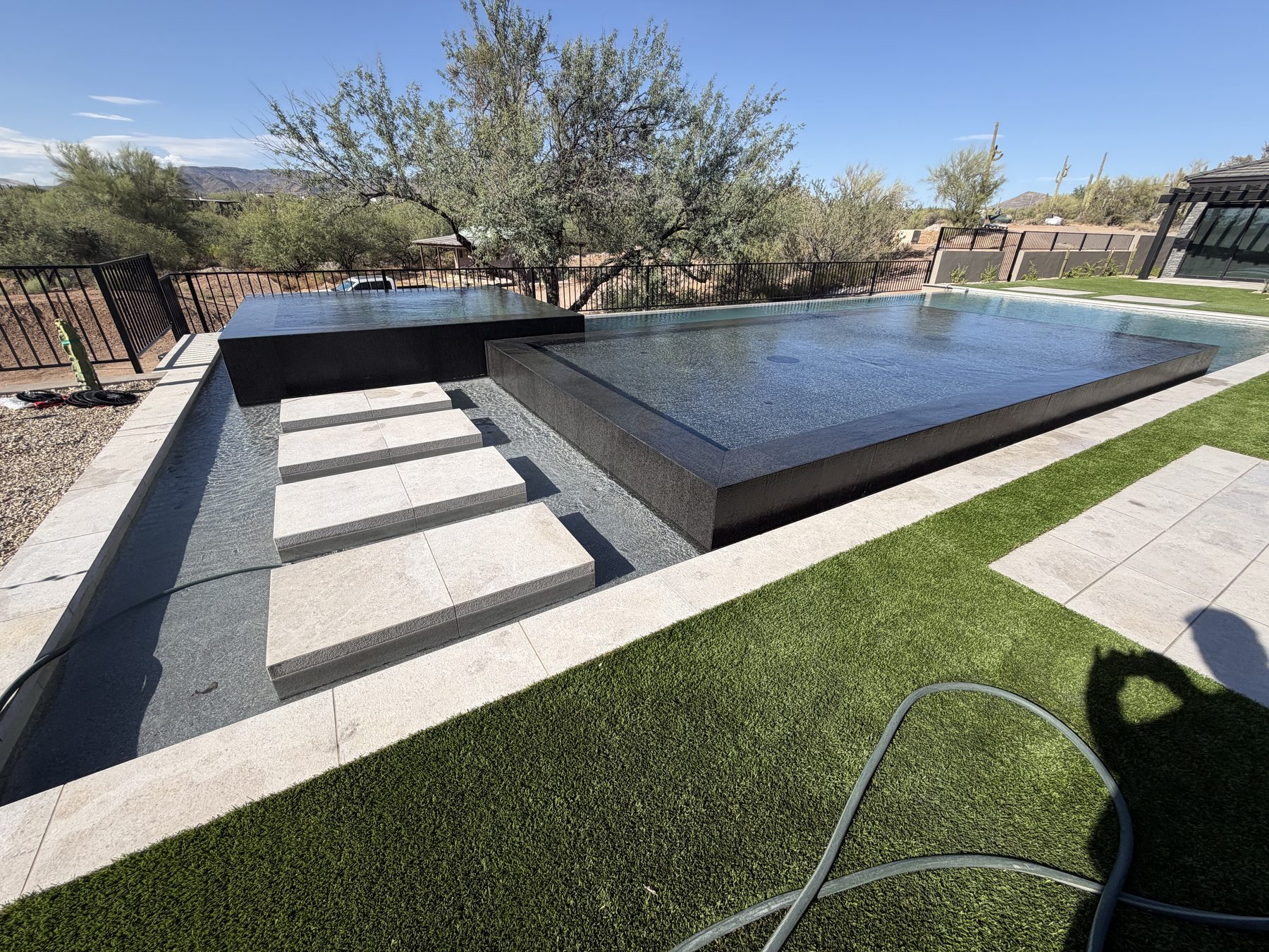 Raised perimeter-overflow spa sheeting water over its edges — Standard Pools project