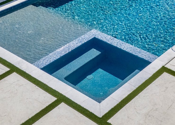 Square spa set at deck level with turf and paver surround