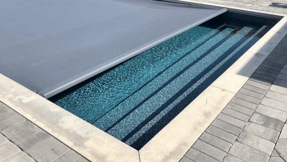 Automated pool cover partly extended over a pool