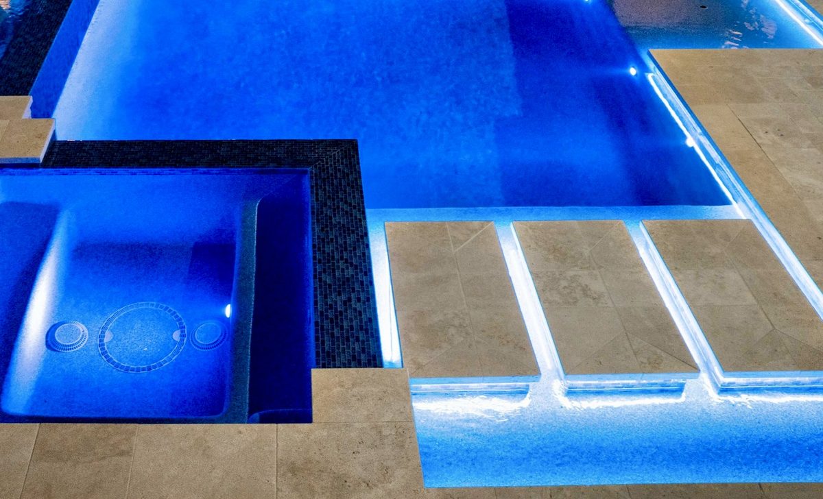 Pool and spa lit blue with LED lighting at night